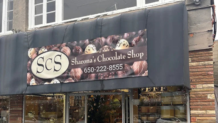 storefront with 'Sharon's Chocolate Shop' sign and contact number